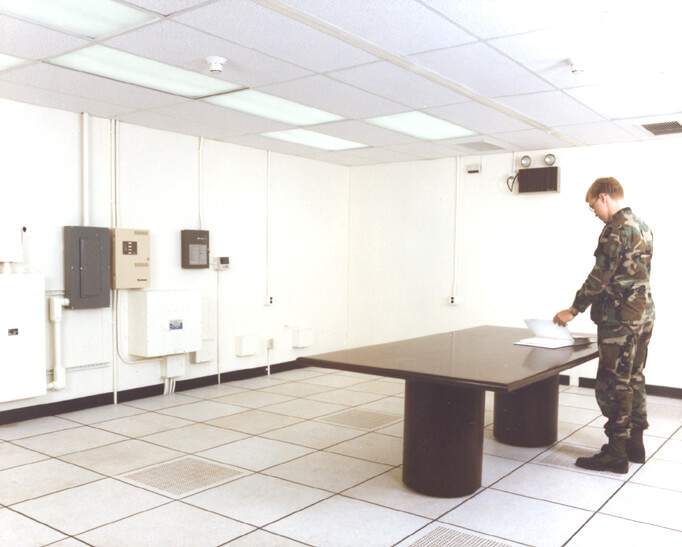 mann i uniform står ved bord i avlyttingsikkert rom