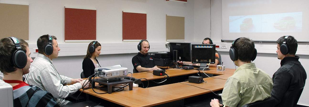 mennesker sitter i et lytterom med hodetelefoner på ørene